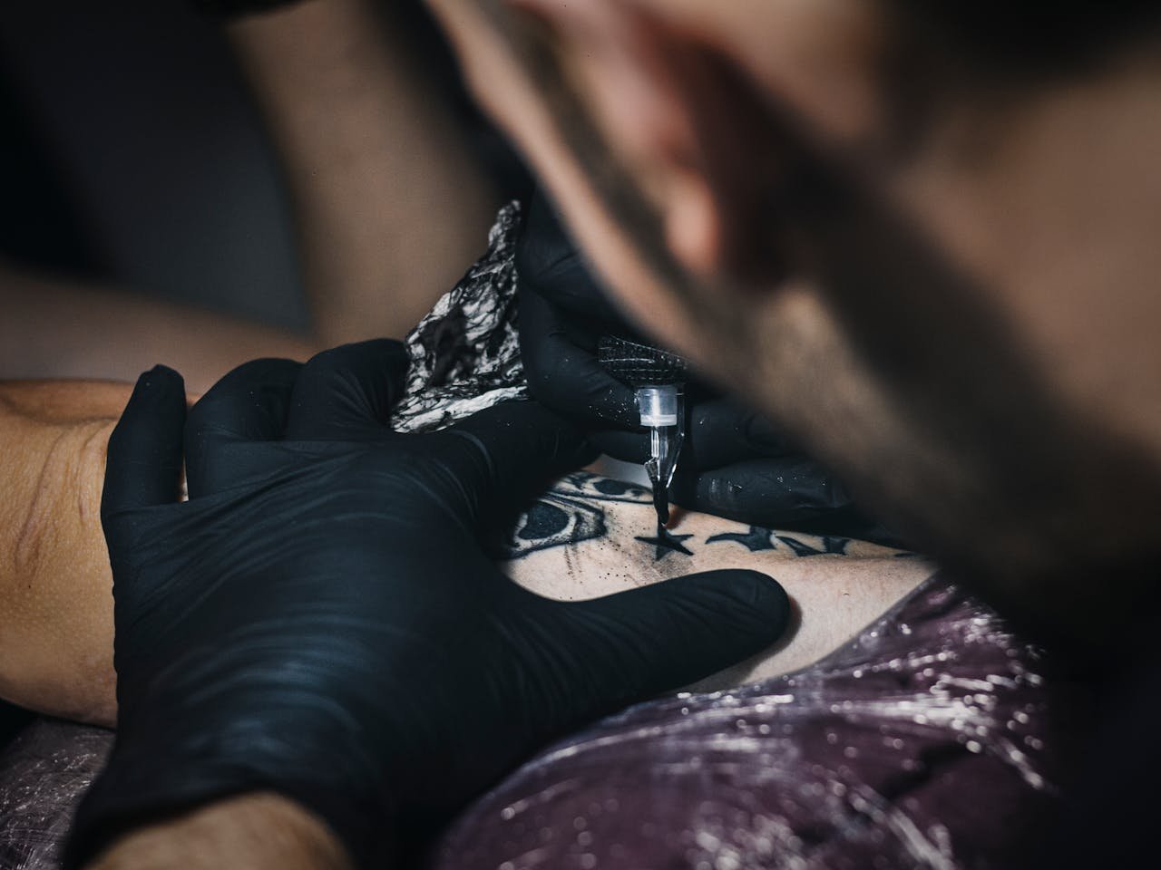 Detailed image of a tattoo artist at work, focusing on intricate design creation.